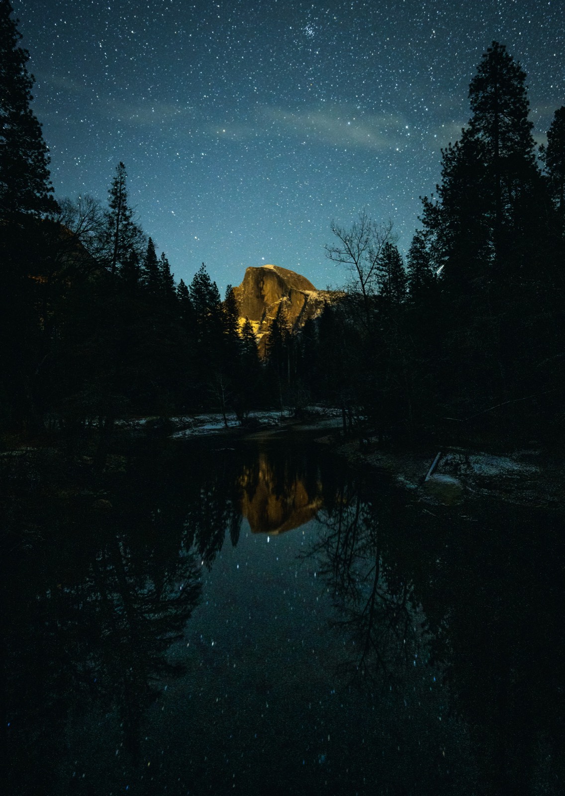 Starry night sky over a mountain lake